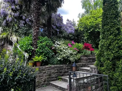 a garden with flowers and plants on a stone wall at Garden Apartment Villa Corazza in Tirolo