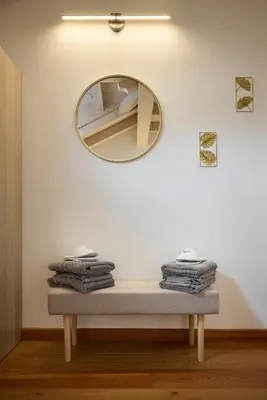 a mirror on a wall above a table with towels at Apartment Alpen Dolomites in Selva di Cadore