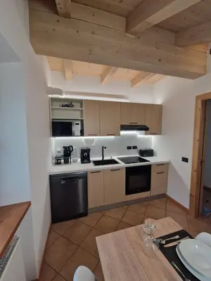 a kitchen with wooden cabinets and a wooden table at Apartment Alpen Dolomites in Selva di Cadore