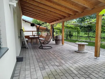 a covered patio with a swing and a table at Ferienwohnungen HÖLLERHOF in Terlan in Vilpiano
