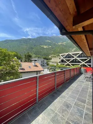 a balcony with a red fence and mountains in the background at Penthouse Ferienwohnung- 3 Schlafzimmer in Naturno