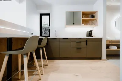 a kitchen with a counter and two chairs in a room at Stricker Aparthotel in Tirolo