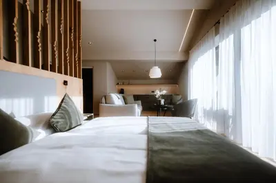a large white bed in a room with windows at Stricker Aparthotel in Tirolo