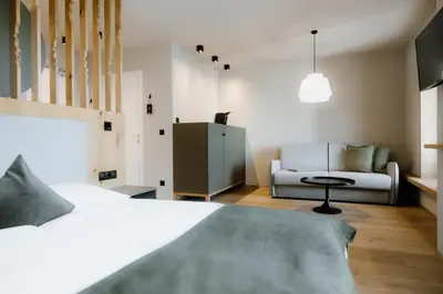 a bedroom with a bed and a couch at Stricker Aparthotel in Tirolo