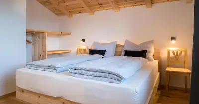 a bedroom with two beds with white sheets and pillows at Gestüt Feuerstein- Lanznasterhof in Prato allʼIsarco