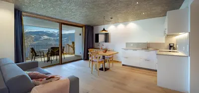 a living room with a couch and a kitchen with a table at Gestüt Feuerstein- Lanznasterhof in Prato allʼIsarco