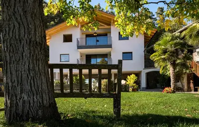 a park bench sitting in front of a tree at Gestüt Feuerstein- Lanznasterhof in Prato allʼIsarco