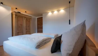 a bedroom with a white bed with pillows on it at Gestüt Feuerstein- Lanznasterhof in Prato allʼIsarco