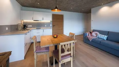 a kitchen and living room with a table and a couch at Gestüt Feuerstein- Lanznasterhof in Prato allʼIsarco