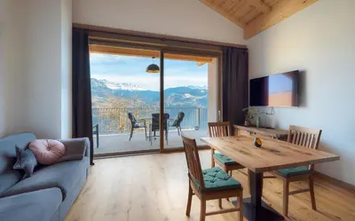 a living room with a table and a view of the mountains at Gestüt Feuerstein- Lanznasterhof in Prato allʼIsarco