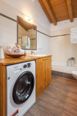 a washing machine in a bathroom with a sink and a tub at DolomiApartments - Appartamento Fiordaliso in Predazzo