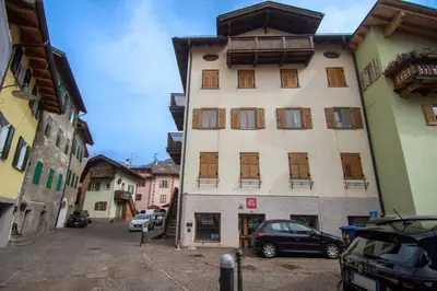 a tall building with cars parked in a parking lot at DolomiApartments - Appartamento Fiordaliso in Predazzo