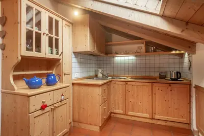 a kitchen with wooden cabinets and a sink at DolomiApartments - Appartamento Fiordaliso in Predazzo