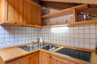 a kitchen with a stainless steel sink and wooden cabinets at DolomiApartments - Appartamento Fiordaliso in Predazzo