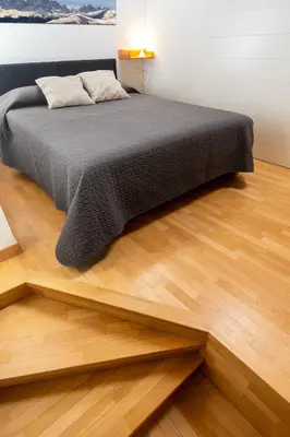 a bed in a room with a wooden floor at DolomiApartments - Appartamento Fiordaliso in Predazzo