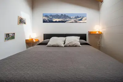 a bedroom with a large bed with two lamps at DolomiApartments - Appartamento Fiordaliso in Predazzo