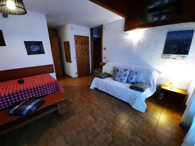 a bedroom with a bed and a couch in a room at Appartamento Fiorella in San Martino di Castrozza