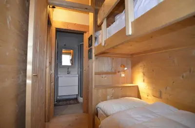 a bedroom with two bunk beds and a bathroom at Villa 5 Torri in Cortina dʼAmpezzo