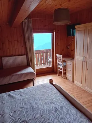 a bedroom with a bed and a desk and a window at Eggernhof in Lauregno