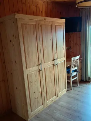 a large wooden cabinet in a room with a chair at Eggernhof in Lauregno