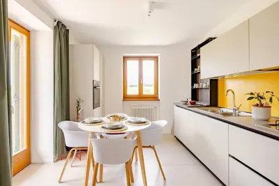 a kitchen with a white table and white chairs at Casa Pradiei Dolomiti View in Cavareno