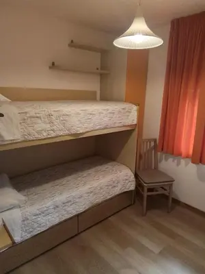 a bedroom with two bunk beds and a chair at Una vacanza in Trentino da ricordare in Mezzano