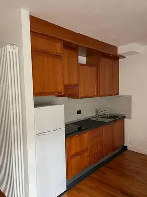 a kitchen with wooden cabinets and a white refrigerator at A casa di Cato in Merano