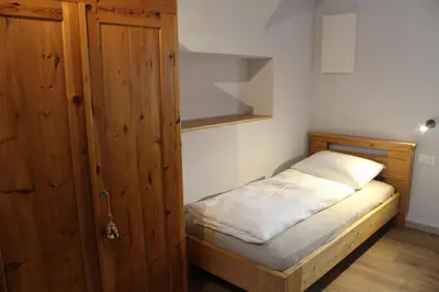 a small bedroom with a bed and a wooden cabinet at Oberkrösserhof in San Lorenzo di Sebato