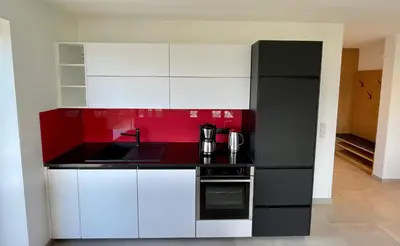 a kitchen with a black refrigerator and white cabinets at Unterlechnerhof in Vollan