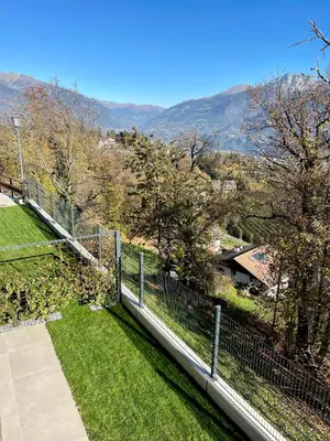 a fence in front of a yard with mountains in the background at Unterlechnerhof in Vollan