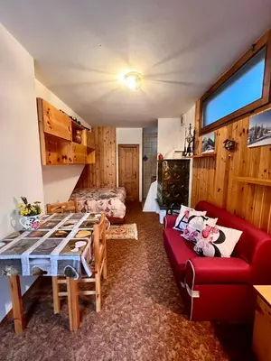 a living room with a table and a red couch at Ciasa AGB in Moena