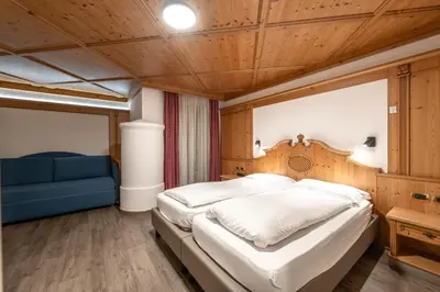 a bedroom with a large bed and a blue couch at EL CIASEL in Canazei