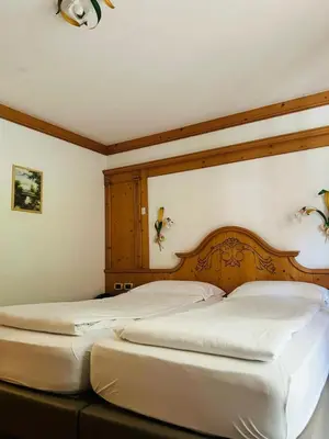 two beds in a bedroom with a wooden headboard at EL CIASEL in Canazei