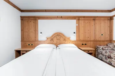 a bedroom with two beds and a chair at EL CIASEL in Canazei