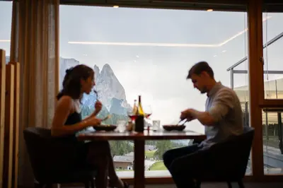 a man and woman sitting at a table in a restaurant at Berghotel Zorzi in Alpe di Siusi