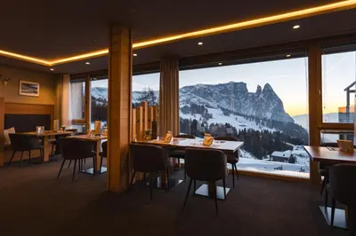 a restaurant with tables and chairs and a mountain view at Berghotel Zorzi in Alpe di Siusi