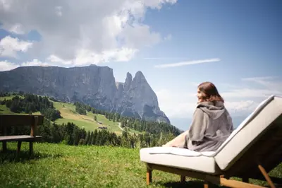 a woman sitting on a chair in the mountains at Berghotel Zorzi in Alpe di Siusi