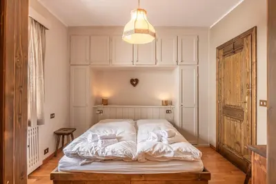 a white bed in a room with a light at Casa Carina in Cortina d Ampezzo in Cortina dʼAmpezzo