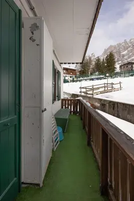 a porch of a building with a green door and snow at Casa Carina in Cortina d Ampezzo in Cortina dʼAmpezzo