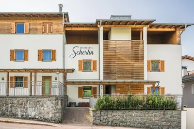 a large white building with a stone wall at Apartments Scherlin in Castelrotto