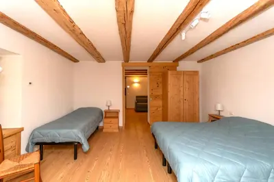 a bedroom with two beds and wooden floors at Appartamento Focobon in Falcade