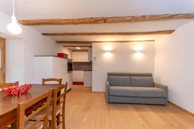 a kitchen and dining room with a table and a couch at Appartamento Focobon in Falcade