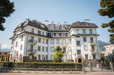 a large white building with a brown roof at Eden House Experience in Merano