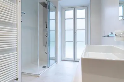 a white bathroom with a shower and a sink at Eden House Experience in Merano