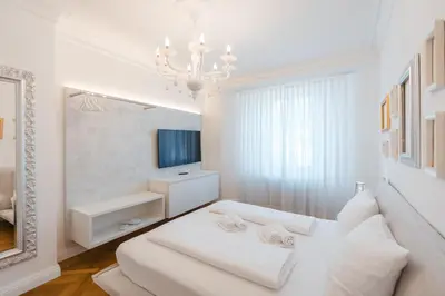 a white living room with a white couch and a television at Eden House Experience in Merano