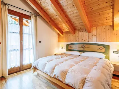 a bedroom with a large bed with a wooden ceiling at Apartment Condominio Parco degli abeti by Interhome in Canazei