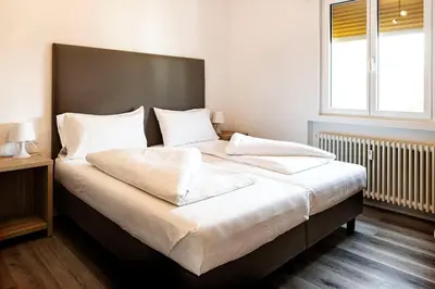 a bedroom with a large bed with white sheets and pillows at Roma Ariston 10 in Bolzano