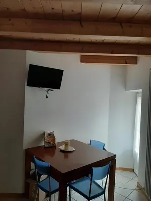 a dining room table with chairs and a television on a wall at Accogliente Bilocale in centro a Predazzo in Predazzo