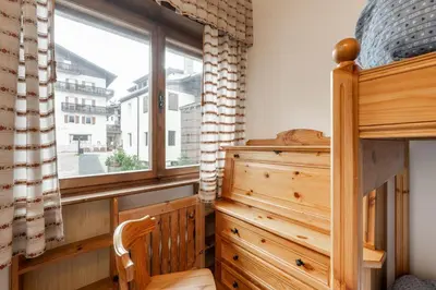 a bedroom with a wooden dresser and a window at Lovely 2 bedroom flat in Corso Italia with parking in Cortina dʼAmpezzo
