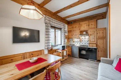 a living room with a table and a kitchen at Lovely 2 bedroom flat in Corso Italia with parking in Cortina dʼAmpezzo